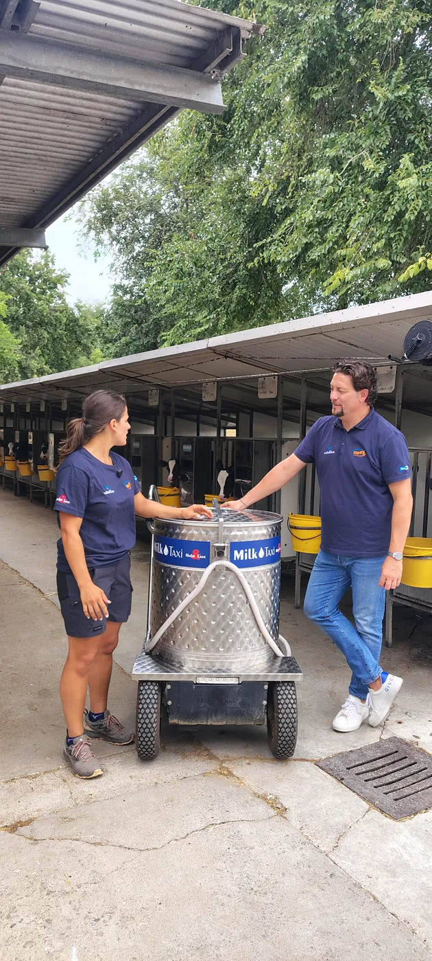 Due persone accanto a MilkTaxi in un allevamento